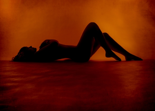 Naked sexy woman silhouette lying at orange background